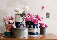 pink flowers are in tins on a table