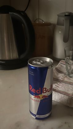 a can of red bull energy drink sitting on a counter next to an electric kettle