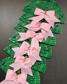 several pink bows are attached to green circuit boards with sequins and beads on them