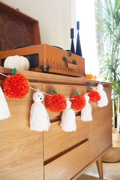 some pom poms are hanging from a dresser in a room with pumpkins