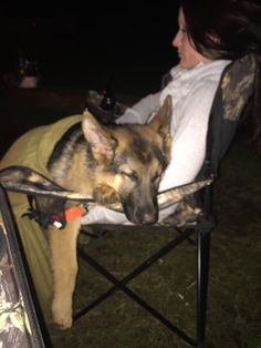 a woman sitting in a folding chair with a dog on it's lap looking at the camera