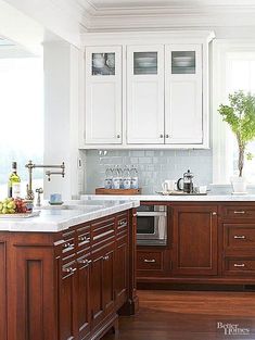 a kitchen with white cabinets and wood floors