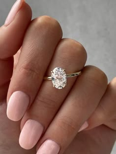 a woman's hand holding a ring with a white diamond on the middle finger