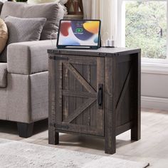 a laptop computer sitting on top of a wooden table in front of a gray couch