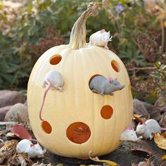 a pumpkin with mouses on it sitting in the leaves