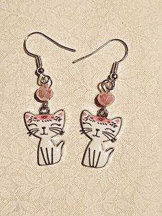 White enamel kitty charm with pink bangs and ear, and 6mm pink accent bead Cute Round Cat Design Jewelry, Cute Cat Design Round Jewelry, Cute Cat Design Jewelry, Whimsical Nickel-free Pink Earrings, Whimsical Pink Nickel-free Earrings, Cute White Jewelry With Charms, Pink Enamel Charms Jewelry, Pink Novelty Dangle Jewelry, Adjustable White Cat Design Jewelry