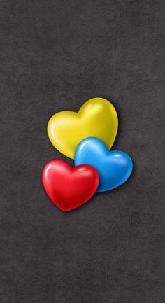 three heart shaped balloons sitting on top of a black surface next to an orange, yellow and blue balloon