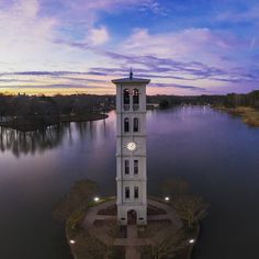 a white clock tower sitting on top of a small island in the middle of a lake