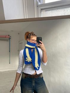 a woman is taking a selfie with her cell phone while wearing a blue and yellow scarf