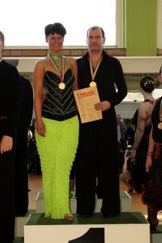 two people standing on top of a green and white pedestal holding an award plaque in front of them