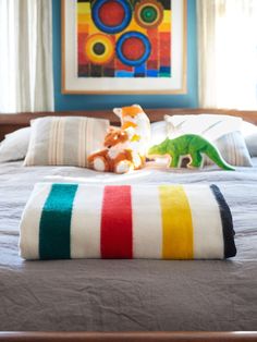 a bed with two stuffed animals on top of it in front of a colorful painting