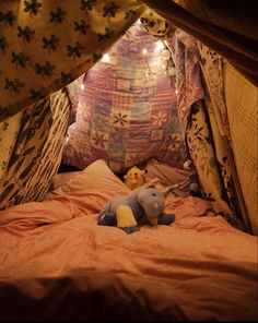 a stuffed animal sitting on top of a bed in a tent