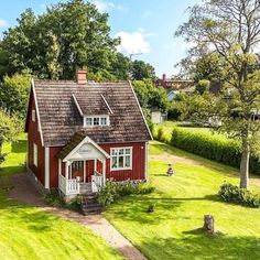 an aerial view of a small red house in the middle of a green yard with trees and bushes