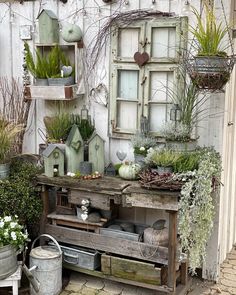 an old wooden table topped with lots of potted plants next to a white building