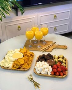 two trays filled with fruit, crackers and orange juice on top of a table