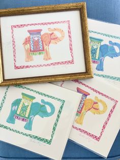 four framed pictures with elephants on them sitting in front of a blue chair and a gold frame