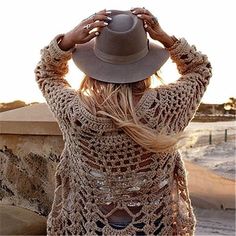 a woman wearing a hat standing on the beach