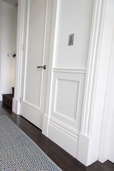 an empty room with white walls and wood floors, along with a blue rug on the floor