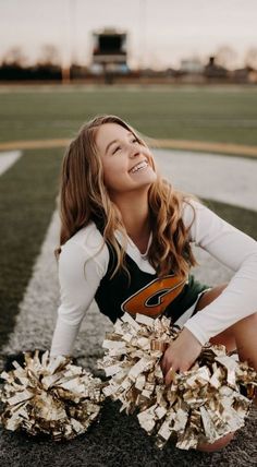 a young woman sitting on the ground holding a cheerleader's pom - pom