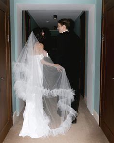 the bride and groom are dressed up in black tuxedos, veils, and gowns