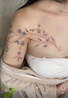 a woman's shoulder with blue flowers on her left arm and the top half of her body