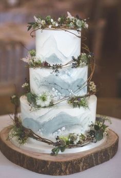 a three tiered wedding cake with white frosting and greenery