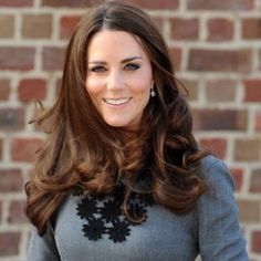 the duke and duchess of cambridge smile as they stand in front of a brick wall