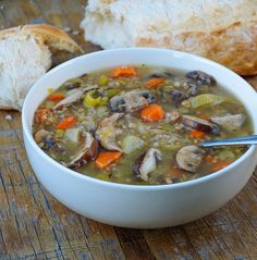 a bowl of soup with carrots, mushrooms and bread