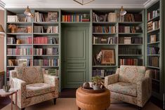 a living room filled with lots of bookshelves next to two chairs and a coffee table