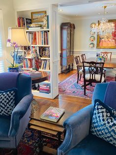 a living room filled with blue couches and chairs next to a dining room table