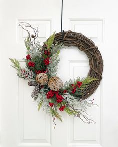 a wreath hanging on the front door decorated with berries and greenery is ready to be hung