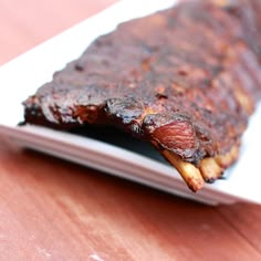 a piece of meat sitting on top of a white plate next to a wooden table