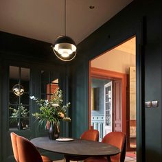 a dining room table surrounded by chairs and potted plants