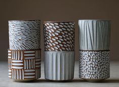 four ceramic vases sitting side by side on a table