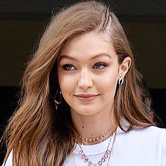 a close up of a person wearing a white shirt and some necklaces on her neck