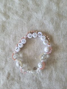 two bracelets with buttons and beads on top of a white cloth covered tablecloth