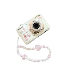 a white camera sitting on top of a white table next to a pink beaded necklace