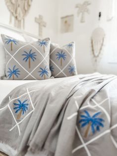 a bed with white sheets and blue palm trees on it