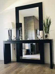 a mirror sitting on top of a wooden table next to a lamp and potted plant