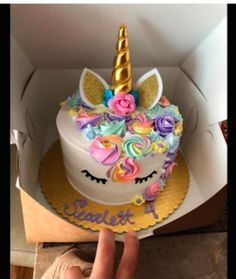 someone is holding up a cake in a box with unicorns on it and flowers