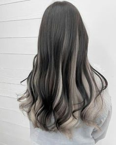 the back of a woman's head with long, wavy hair in grey and white