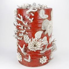 a red vase with white corals and seaweed on it's sides is shown against a white background