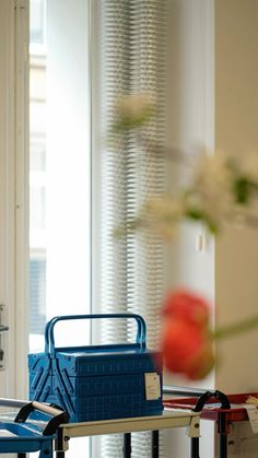 a blue suitcase sitting on top of a metal table next to a vase with flowers