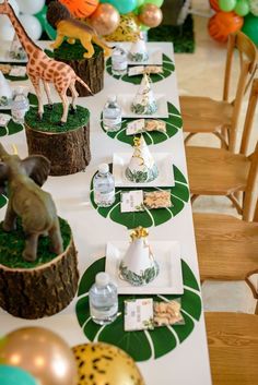 the table is set up for a party with giraffes and other decorations