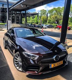 a black mercedes cla parked in front of a gas station on the side of the road