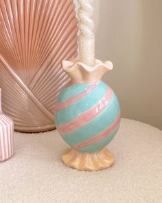 a blue and pink striped vase sitting on top of a white table next to other decorative items