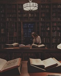 a woman sitting at a table in front of an open book shelf filled with books