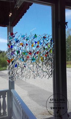 a glass sculpture hanging from the side of a building next to a parking lot on a sunny day