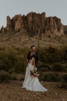 a bride and groom standing in front of a mountain