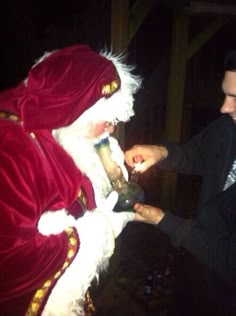 a man dressed as santa clause handing something to someone